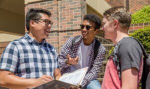 ĵֱ students smiling and talking outside on campus