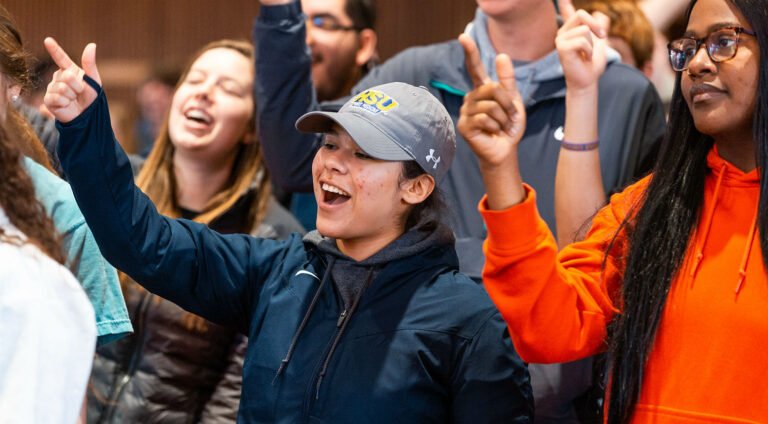 Students do the ĵֱ cheer in chapel.